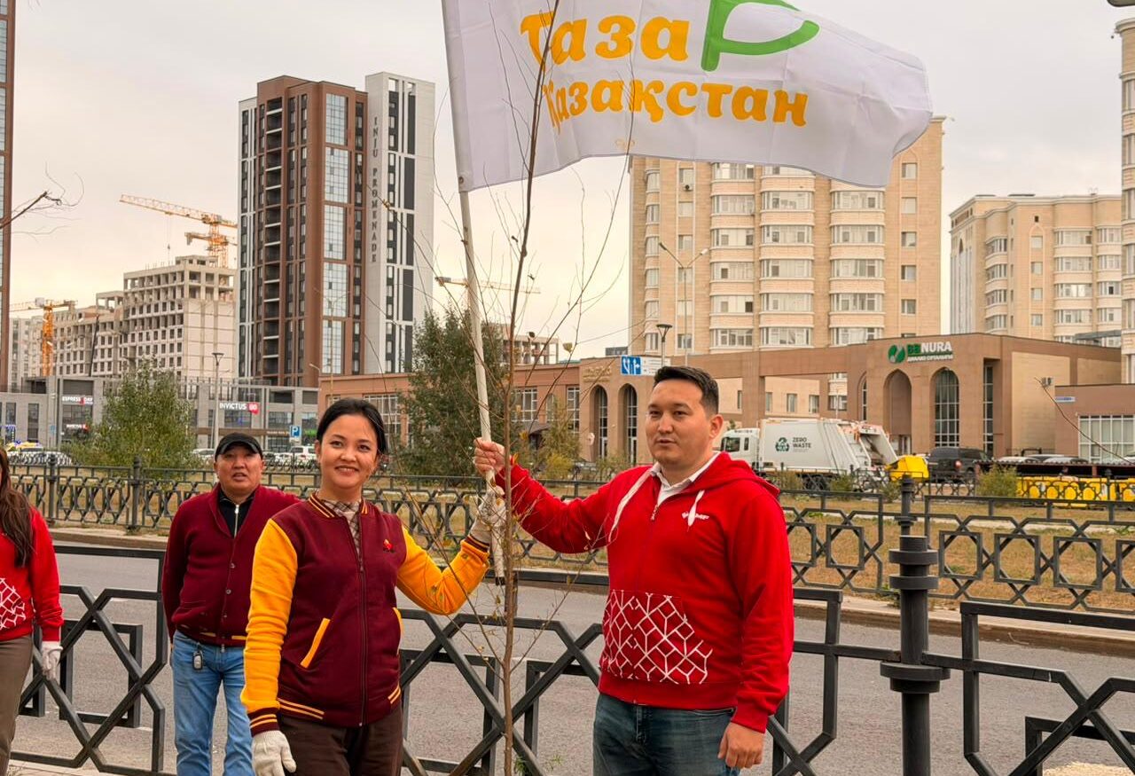 Сотрудники банка высаживают саженцы деревьев вдоль улицы Нажимеденова в Астане